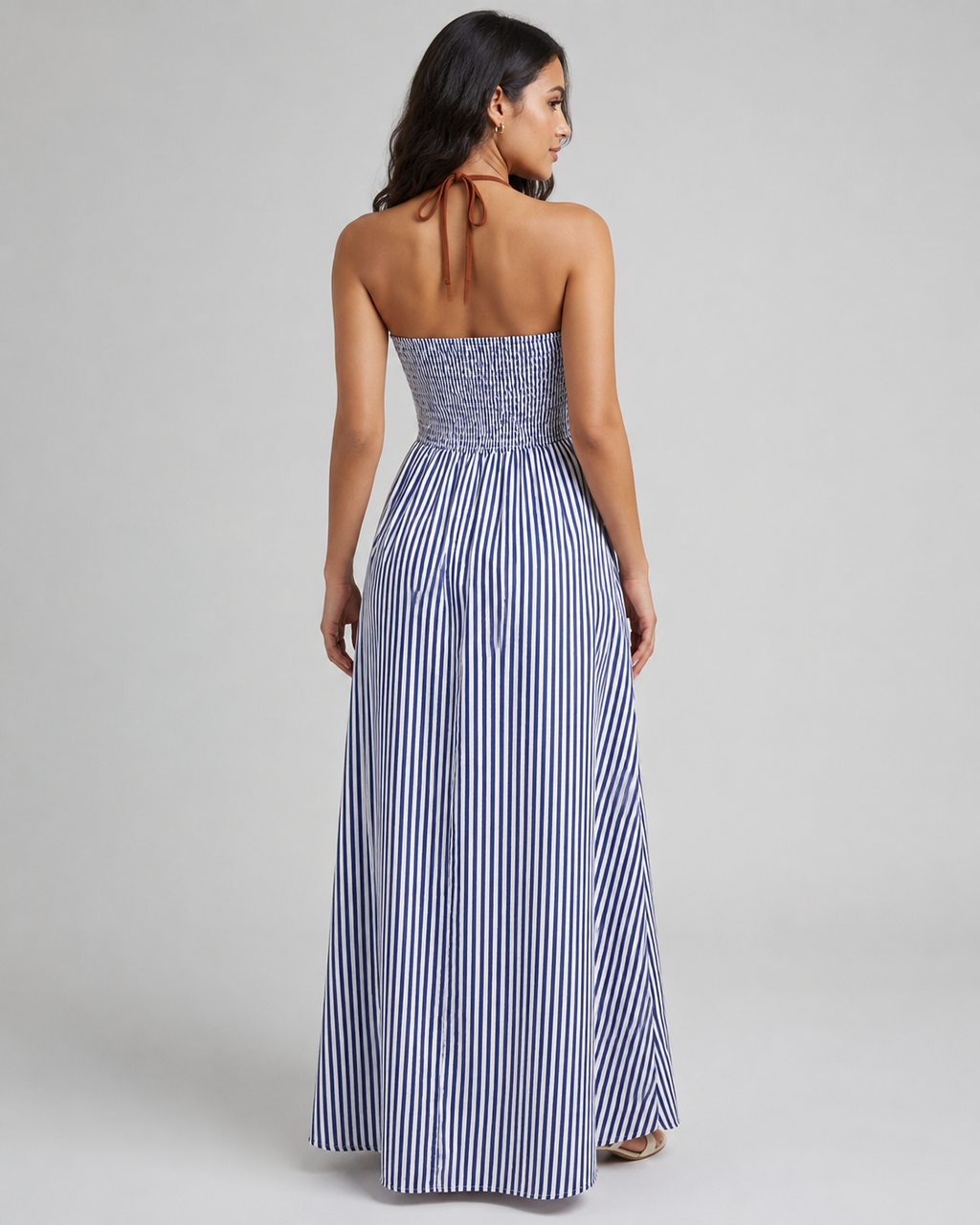 Back view of blue and white striped halter maxi dress featuring a smocked elastic bodice and tie-neck closure.