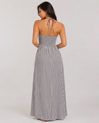 Back view of black and white striped halter maxi dress featuring a smocked elastic bodice and tie-neck closure.